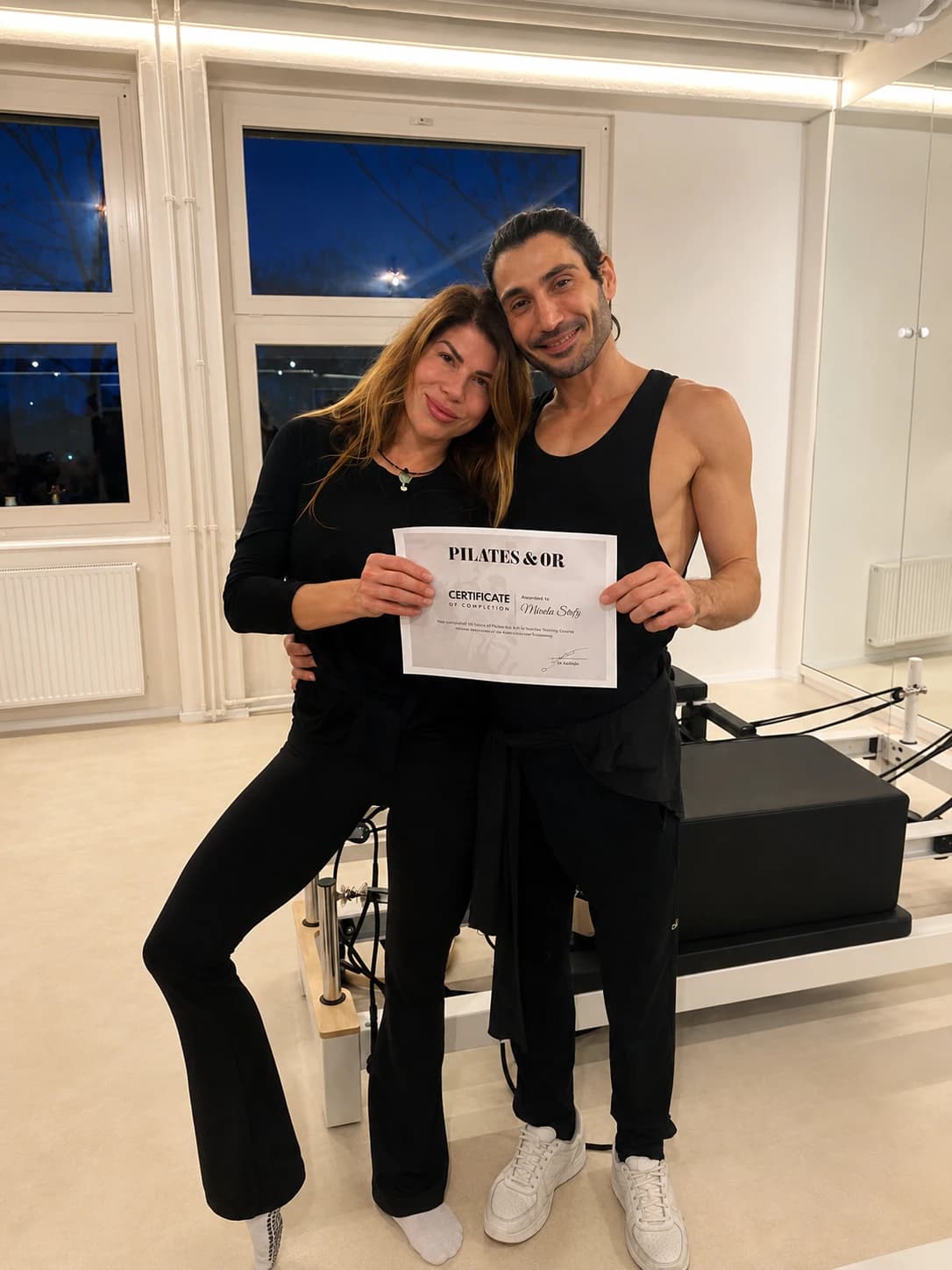Mareike Stretz mit ihrem Ausbildungszertifikat im Studio, im Hintergrund ein Reformer.
